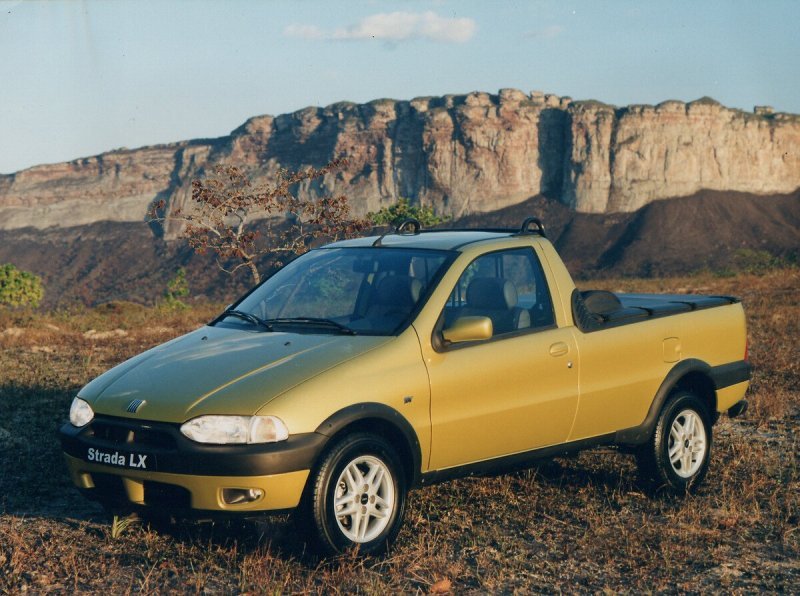Fiat Strada LX 1ª geração dourada estacionada em paisagem de serra, com destaque para o visual original dos anos 2000.