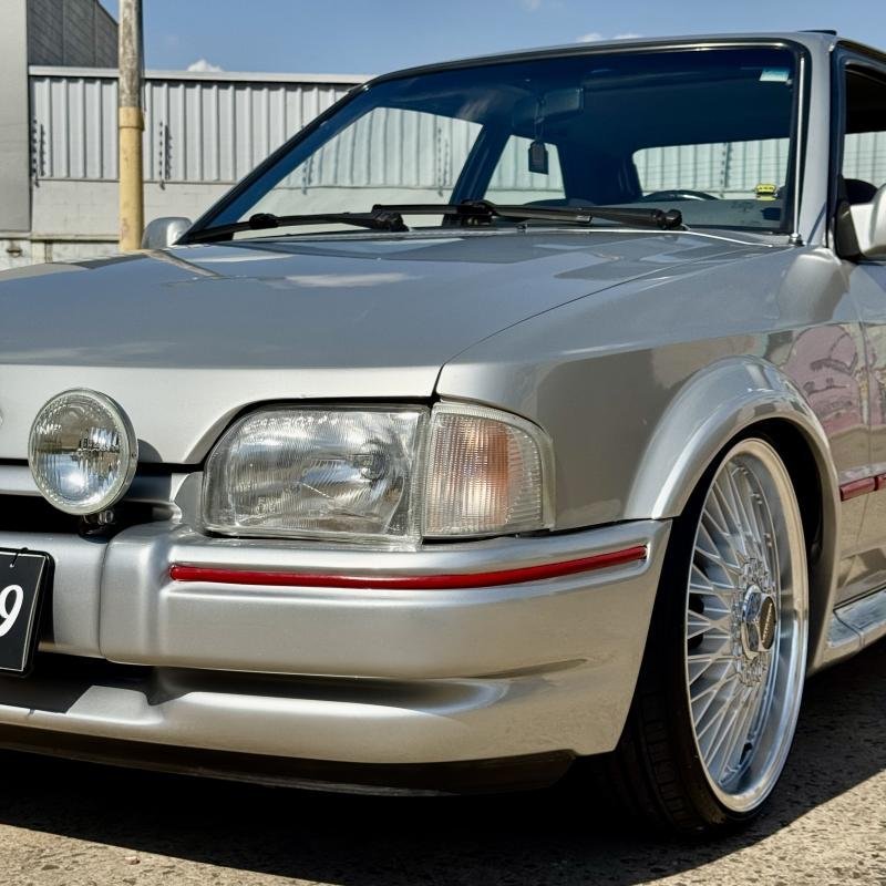 Detalhe do Escort XR3 1990 com faróis de milha e rodas Balina