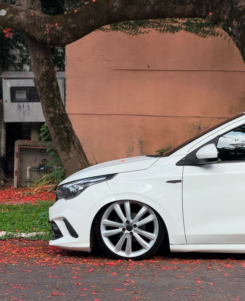 Fiat Argo branco rebaixado visto pela lateral dianteira com fundo de árvore