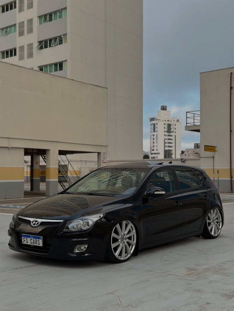 Hyundai i30 preto com suspensão a ar rebaixado no estacionamento, lateral em destaque