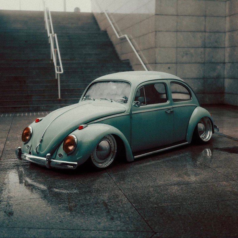 Fusca rebaixado de frente em ambiente urbano molhado