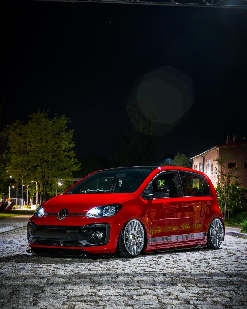 Frente do VW Up vermelho rebaixado com faróis acesos