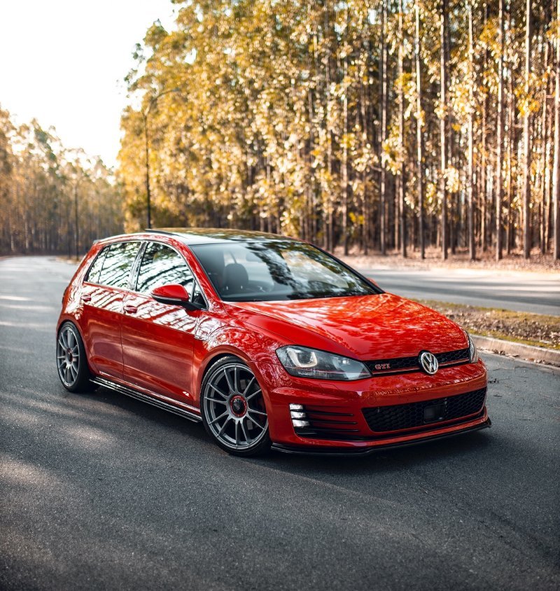 Volkswagen Golf GTI vermelho rebaixado com rodas OZ Racing aro 19 em via urbana, frente 3/4