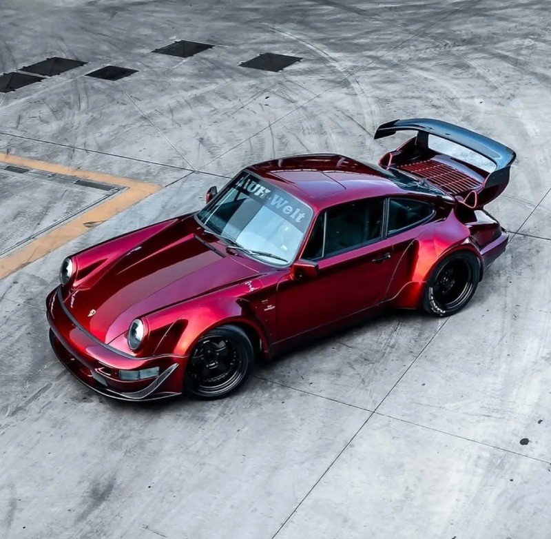 Porsche 964 RWB vermelho rebaixado visto de cima em garagem, com asa elevada e bodykit wide