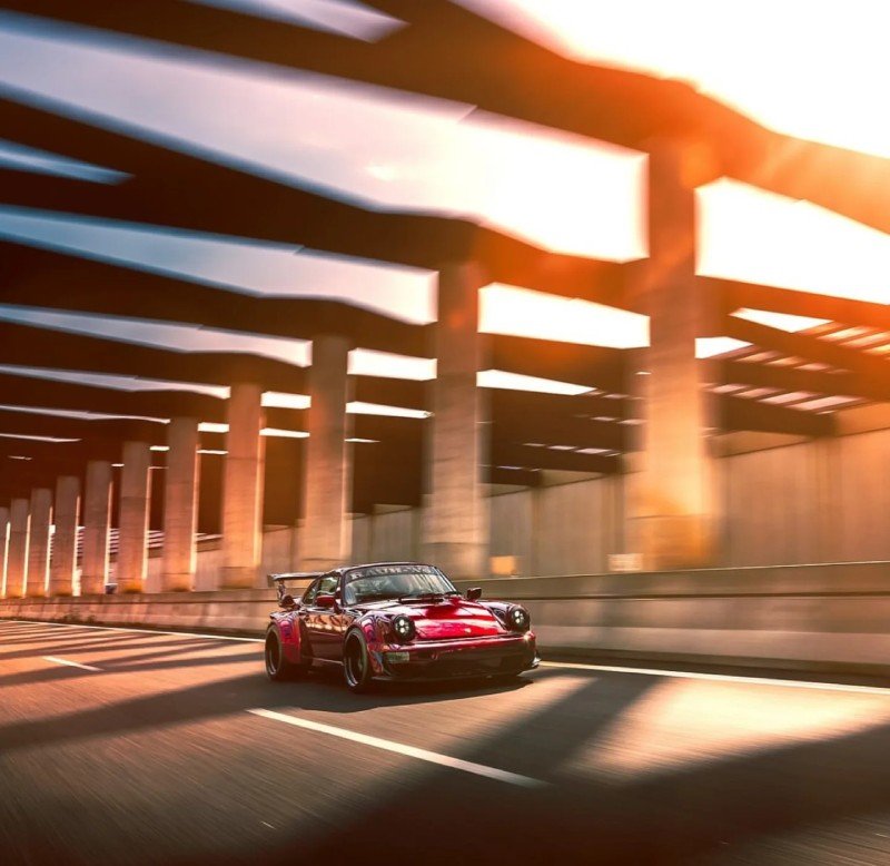 Porsche 964 RWB vermelho rodando em alta velocidade sob viaduto com luz do pôr do sol