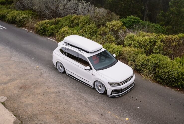 VW Tiguan R-Line branca rebaixada com suspensão a ar e rodas Rotiform, vista superior em estrada com neblina.