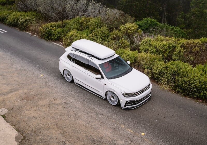 VW Tiguan R-Line branca rebaixada com suspensão a ar e rodas Rotiform, vista superior em estrada com neblina.