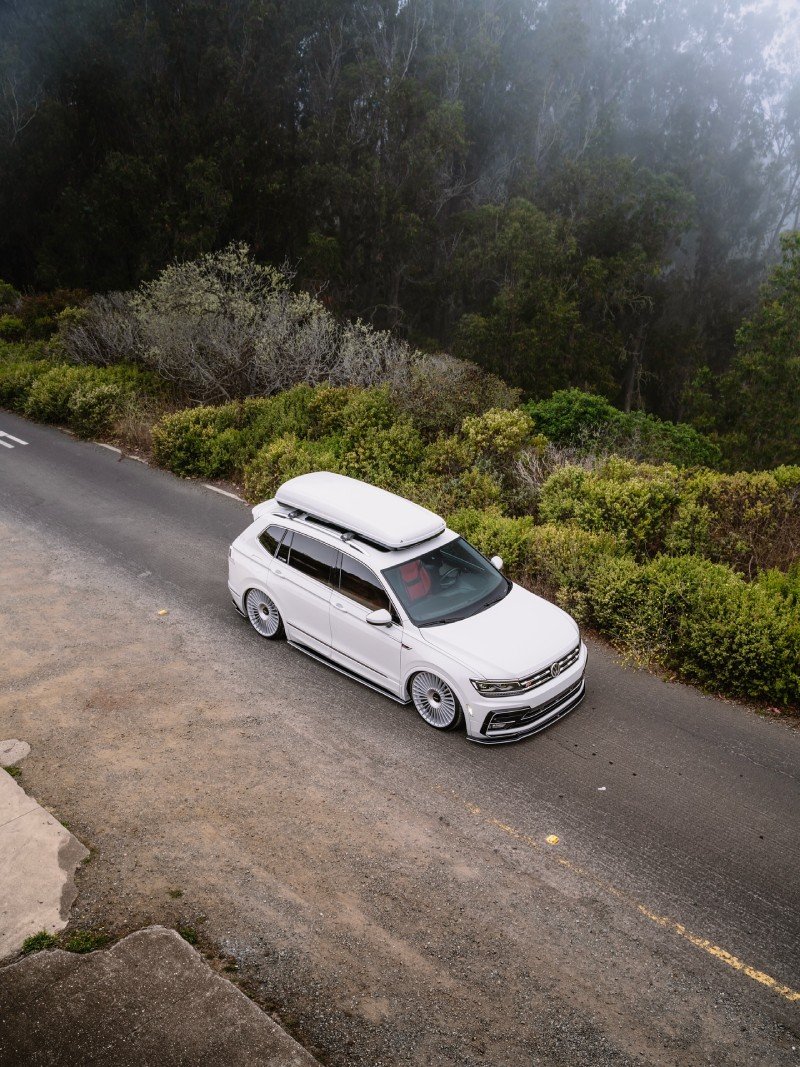 VW Tiguan R-Line rebaixada branca em perspectiva alta com vegetação ao fundo
