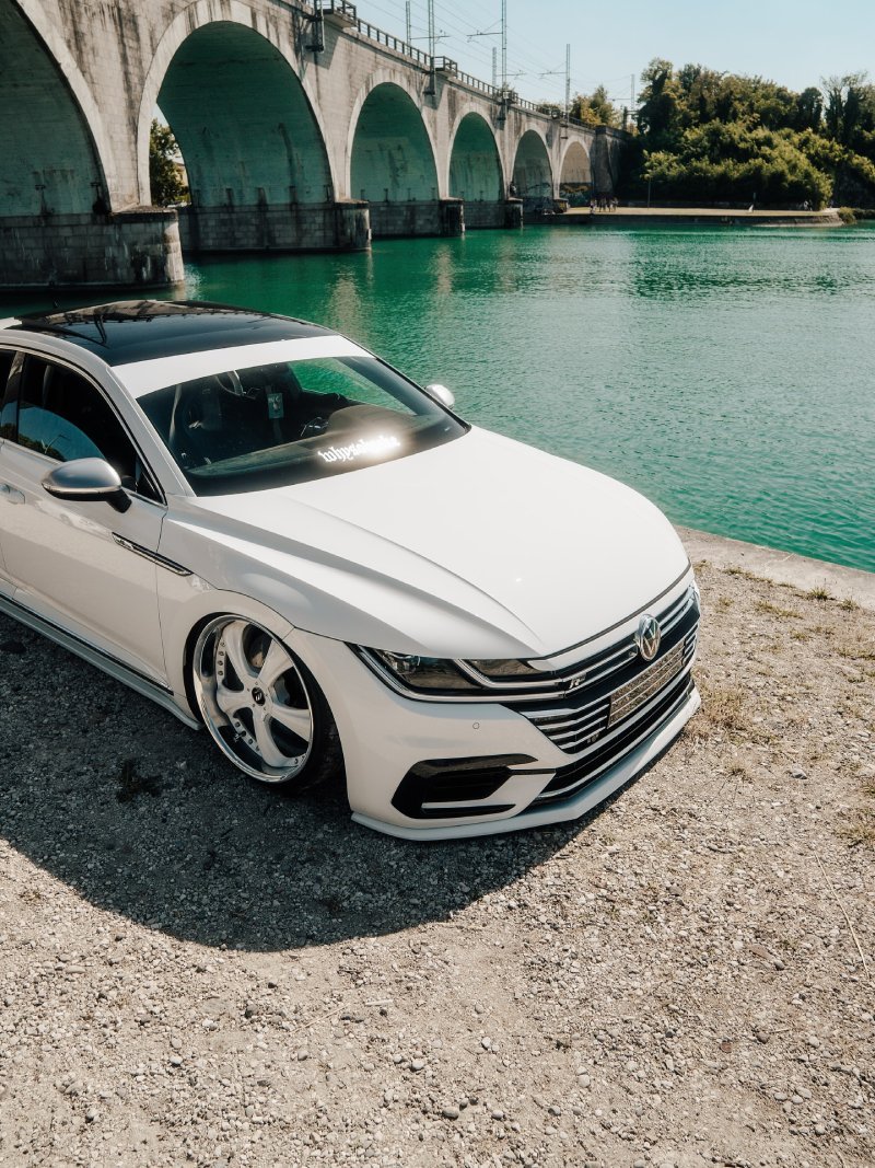 Detalhe do Arteon R-Line rebaixado Detalhe do VW Arteon R-Line branco rebaixado com ponte e água turquesa ao fundo