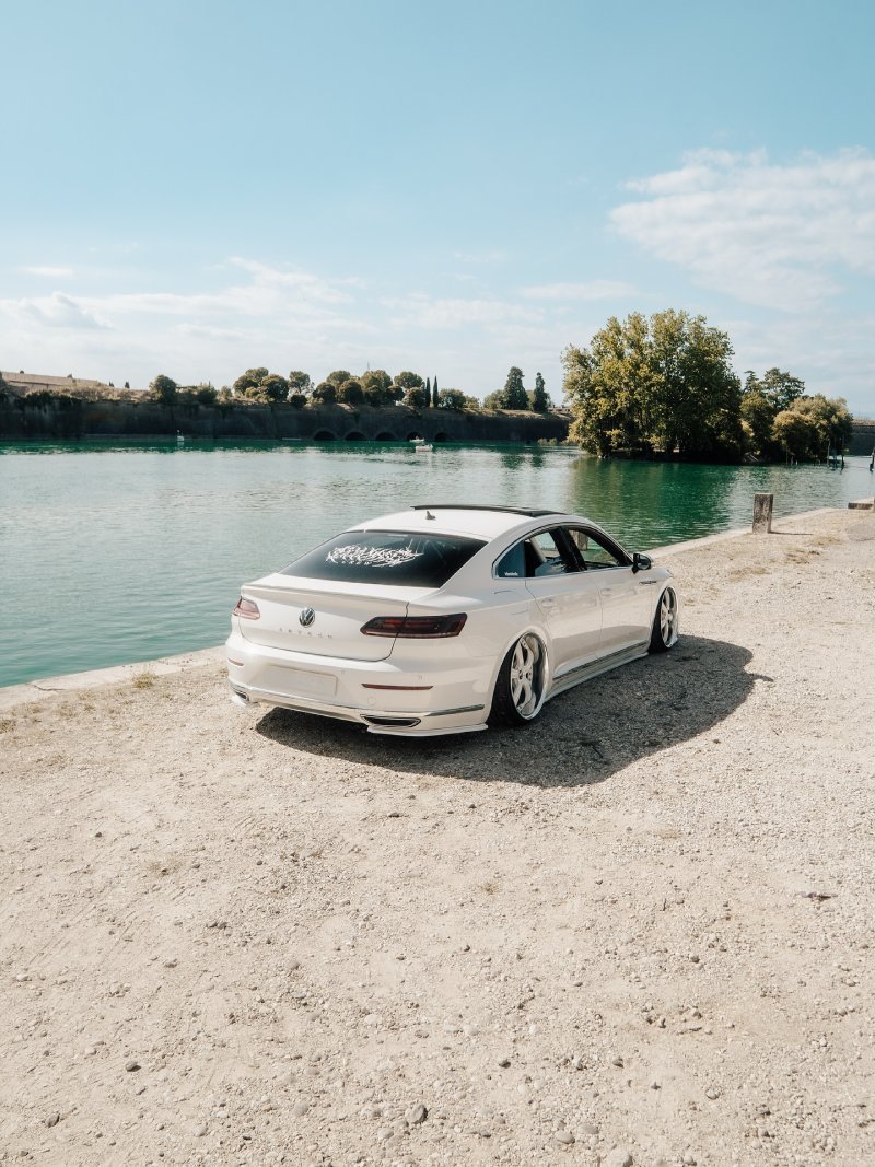 VW Arteon R-Line rebaixado — traseira Volkswagen Arteon R-Line branco rebaixado visto por trás à beira d’água