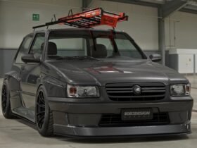 Fiat Uno escada rebaixado cinza com bodykit widebody, rodas pretas e escada laranja no teto em pavilhão
