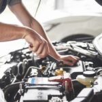 Mecânico realizando reparo de recall gratuito em concessionária autorizado, com motor aberto e ferramentas.