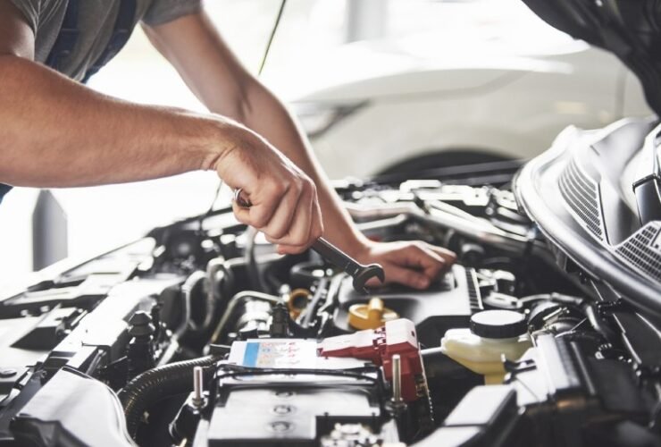 Mecânico realizando reparo de recall gratuito em concessionária autorizado, com motor aberto e ferramentas.