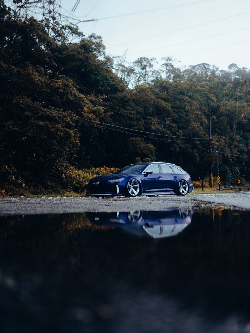 Audi RS6 Avant 2021 azul rebaixada — lateral 3/4 com reflexo na pista