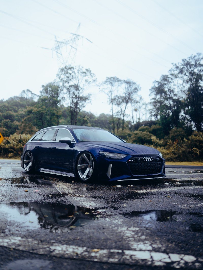 Audi RS6 Avant 2021 azul — frente 3/4 com reflexos na pista