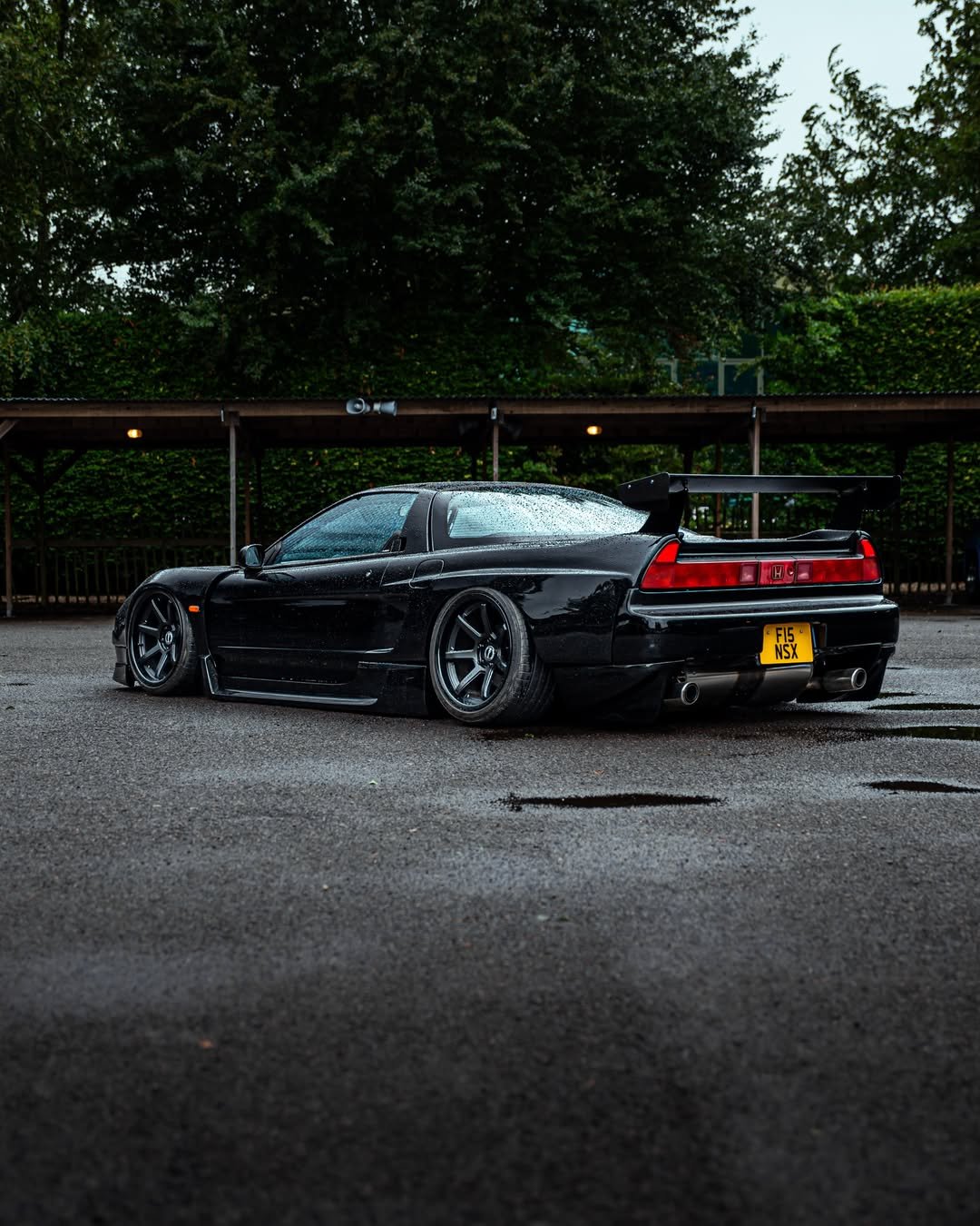 Honda NSX rebaixado preto visto pela traseira com aerofólio grande