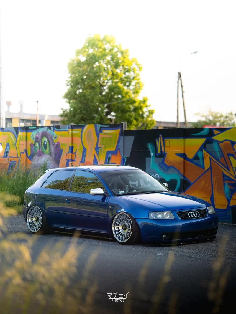Audi A3 azul com rodas grandes e suspensão a ar em cenário urbano Audi A3 azul com visual agressivo e fundo com grafite