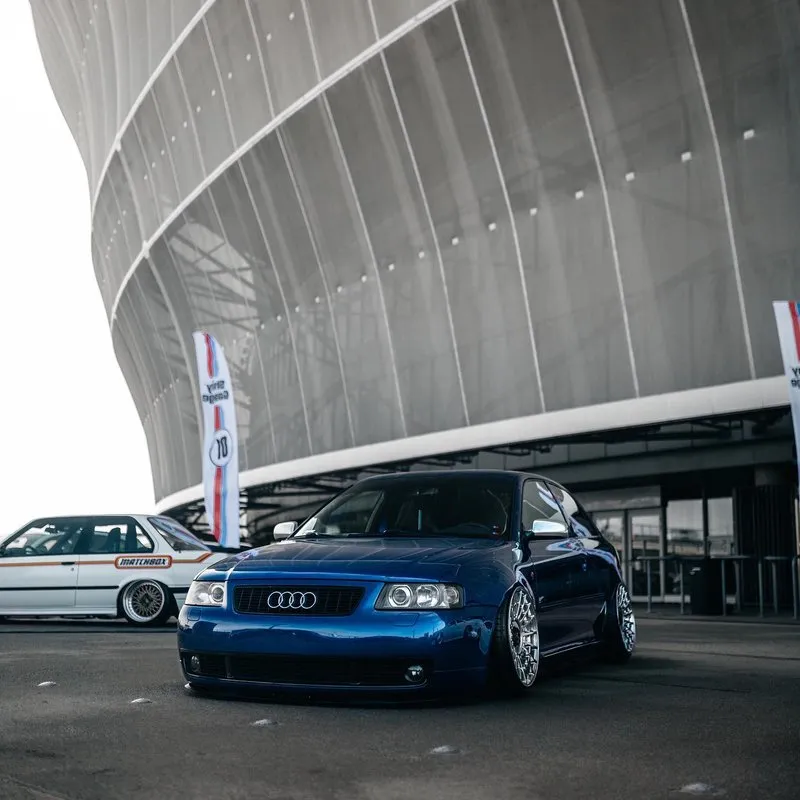 Audi A3 azul rebaixado com suspensão a ar e rodas Rotiform em evento automotivo Audi A3 azul rebaixado com suspensão a ar e rodas Rotiform em evento