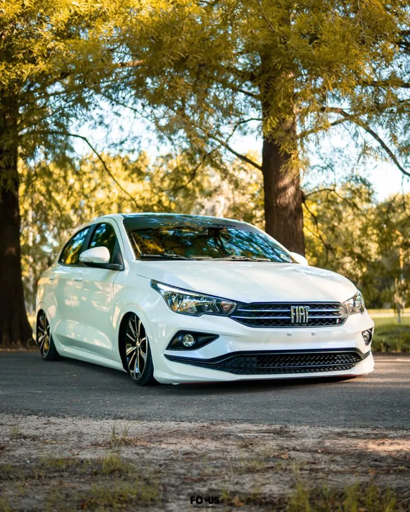 Fiat Cronos branco com suspensão a ar visto de lateral em ambiente arborizado