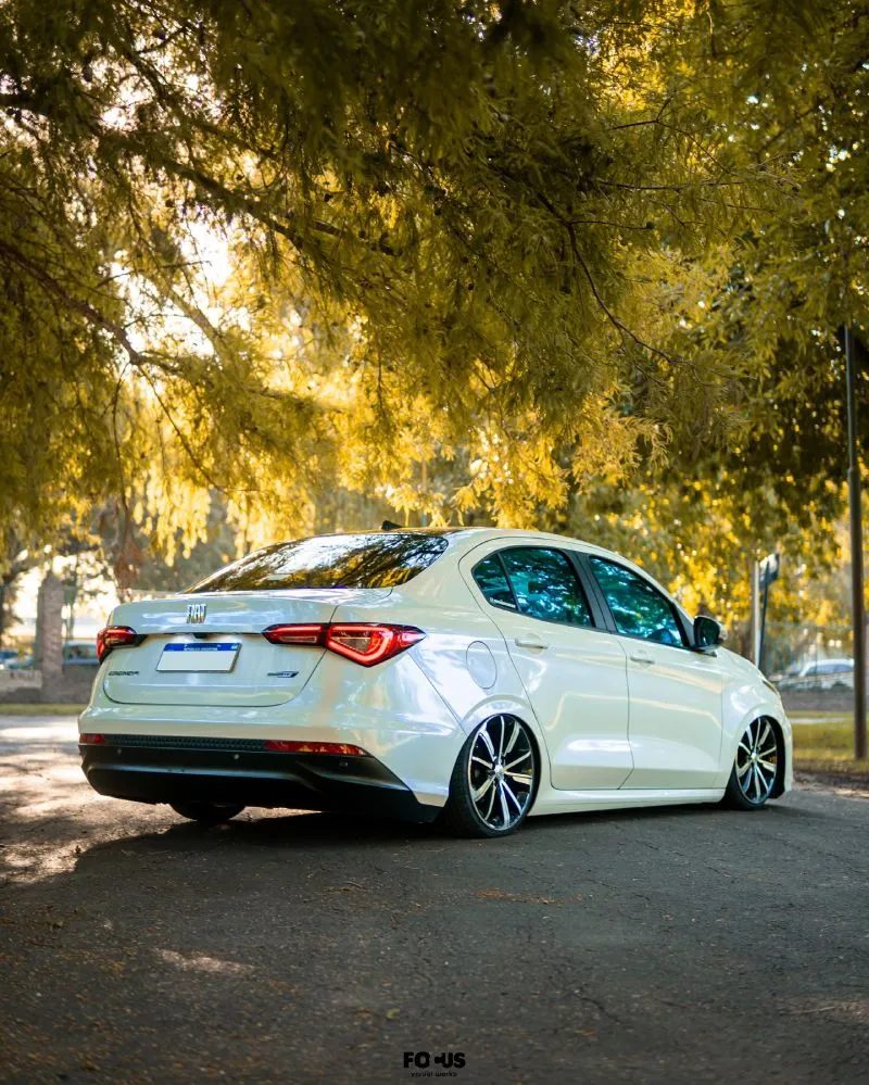 Fiat Cronos branco rebaixado com suspensão a ar em posição lateral com sol ao fundo