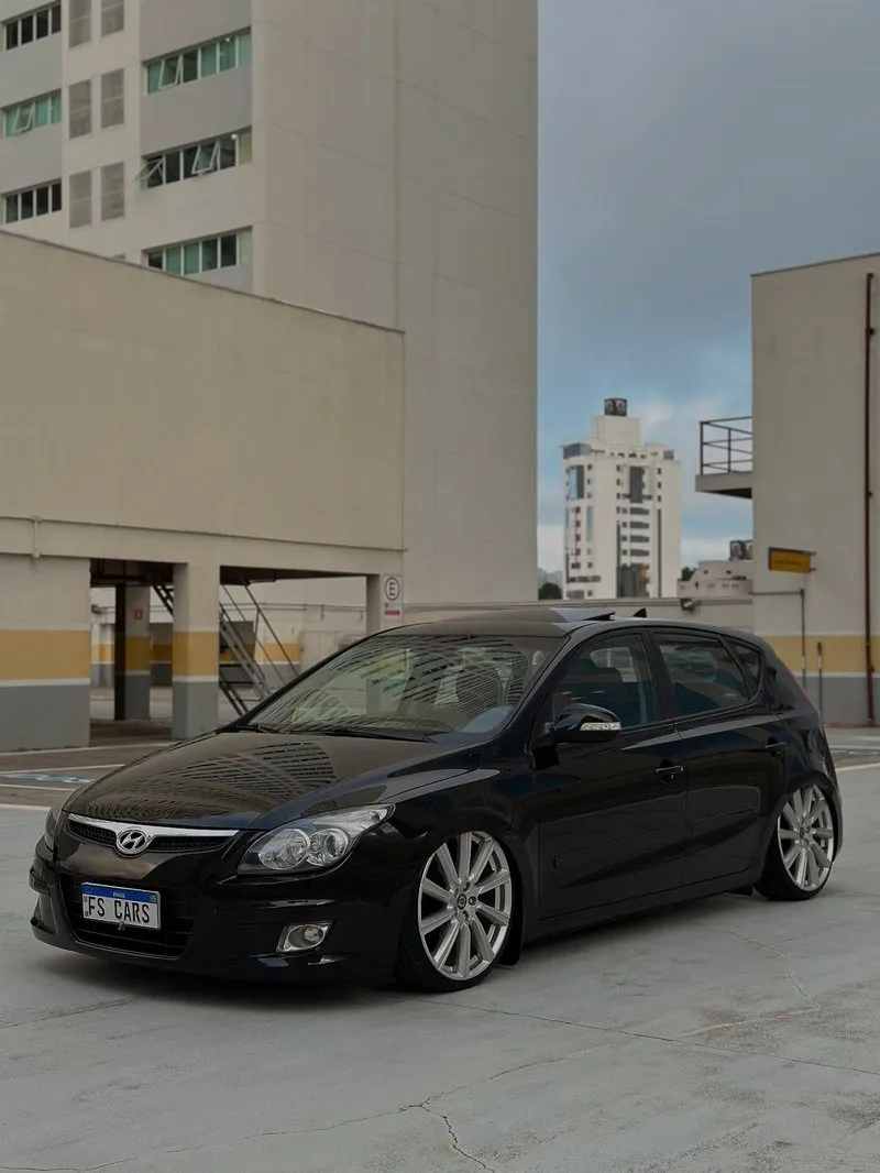Hyundai i30 preto com suspensão a ar rebaixado no estacionamento, lateral em destaque