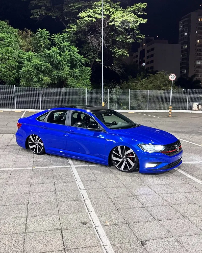 Jetta R-Line rebaixado com rodas aro 20 e envelopamento azul VW Jetta R-Line azul rebaixado visto de frente com LED e rodas esportivas