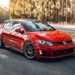 Volkswagen Golf GTI vermelho rebaixado com rodas OZ Racing aro 19 em via urbana