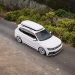 VW Tiguan R-Line branca rebaixada com suspensão a ar e rodas Rotiform, vista superior em estrada com neblina.