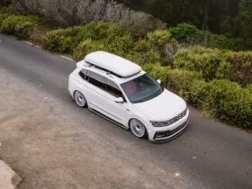 VW Tiguan R-Line branca rebaixada com suspensão a ar e rodas Rotiform, vista superior em estrada com neblina.