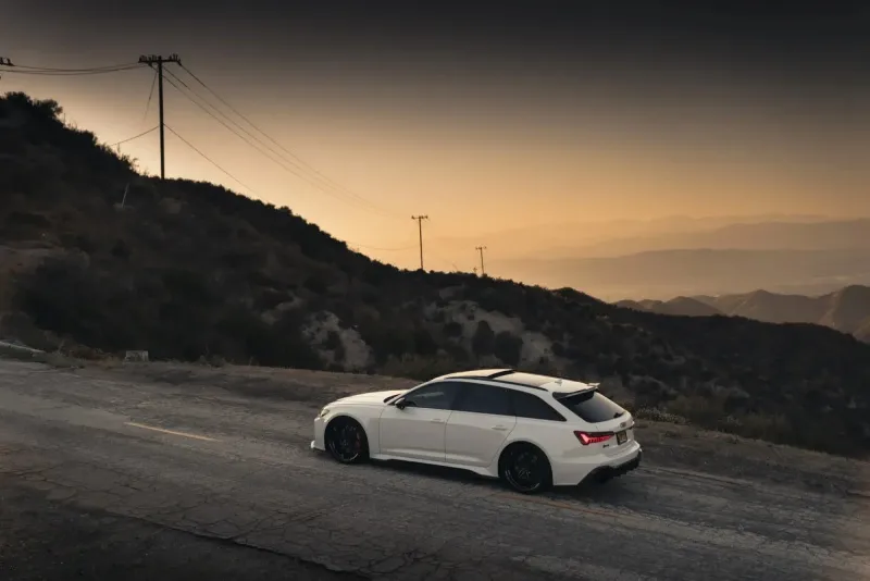 Audi RS6 Avant rebaixada — vista superior lateral Audi RS6 Avant branca rebaixada vista superior lateral em estrada de serra