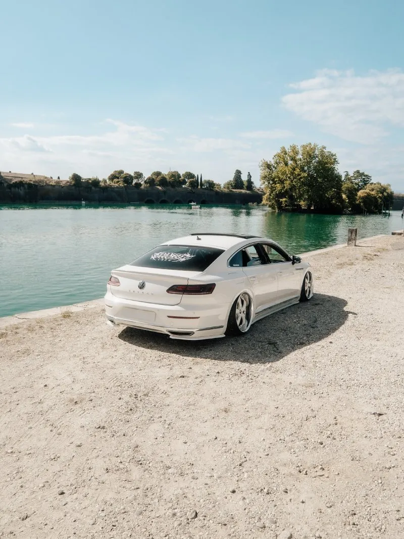 VW Arteon R-Line rebaixado — traseira Volkswagen Arteon R-Line branco rebaixado visto por trás à beira d’água